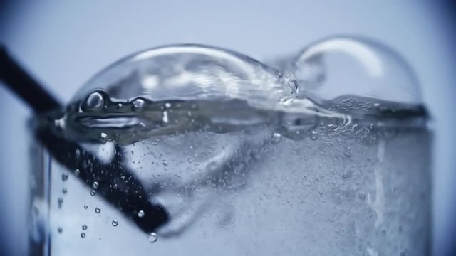 Close up of air bubbles created by someone blowing with straw into full glass of water