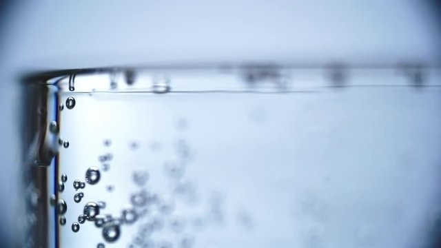 Rack focus of gas bubbles going up to surface in glass of water 