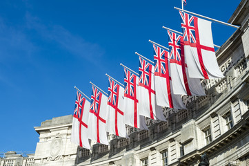 Traditional white ensign flags fly in a row atop Admiralty Arch, the ceremonial gateway between...