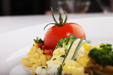 A prepared plate of spaghetti broccoli ready for serving garnished with tomatoes and basil