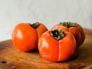 Three persimmon on a wooden board

