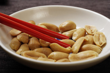 close up of red chopsticks picking up peanuts