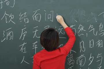 woman writing Chinese characters on chalkboard