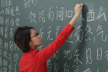 woman writing chinese characters on chalk board