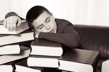 schoolboy sleeping on lot of books