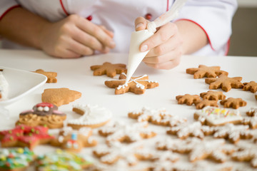 Close up of female confectioner hands decorating gingerbread stars with icing sugar using selfmade pastry bag making cutest Christmas cookies