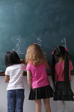 three girls writing on chalk view