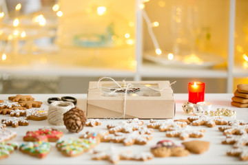 Box of cookies, gingerbread cookies of different shapes displayed on a white desk, the warmth of Christmas in interior, festive lightings and candles. Christmas concept photo