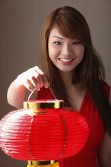 Young woman holding red lantern and smiling