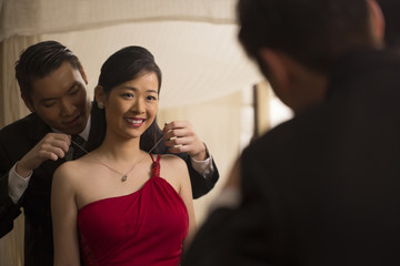Singapore, Man putting necklace on woman in front of mirror