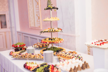 Delicious and tasty dessert table with cupcakes shots at reception closeup