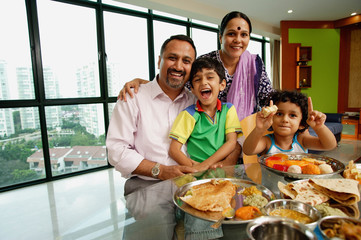 Family of four sitting around dining table, smiling at camera