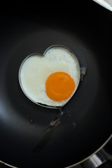 Fried egg on pan and fresh eggs.