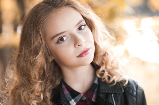 Beautiful blonde teenage girl 12-14 year old wearing leather jacket outdoors. Looking at camera. Autumn season.