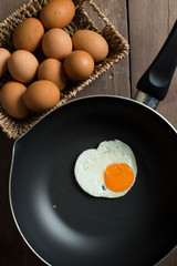 Fried egg on pan and fresh eggs.