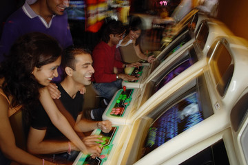 Young adults playing games in video arcade