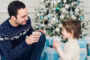 Father with his son sitting relaxed in ski resort chalet and drinking hot tea, joyful winter vacation, people traveling on Christmas holidays
