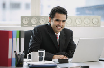 Fototapeta na wymiar Businessman sitting in office, smiling at camera
