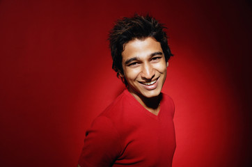 Man in red shirt against red background, smiling, portrait