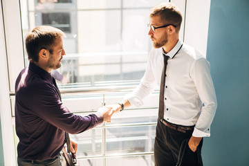 handshake of business partners met on the stairs in the office building