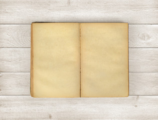 Open old book on wooden background.