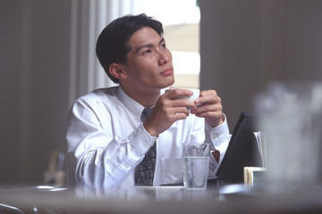 Male executive holding coffee cup in cafe, thoughtful expression