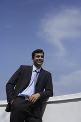 Indian businessman leaning on balcony.