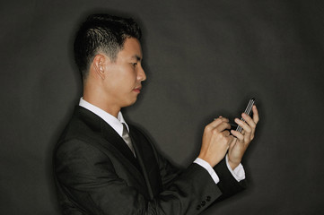 Young man using PDA, standing in profile