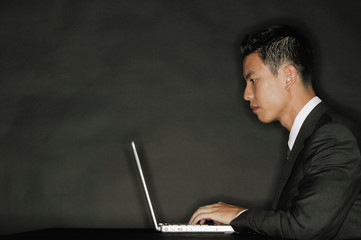 Young man using laptop, side view