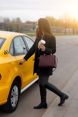 Brunette with long hair, opensing door of yellow taxi