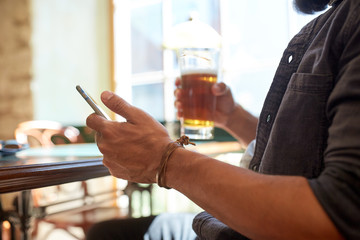 close up of man with smartphone and beer at pub