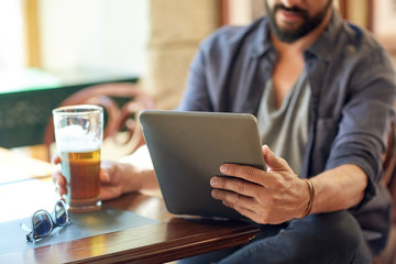 close up of man with tablet pc and beer at pub