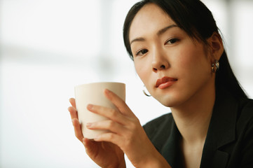 Young woman sitting at desk, holding mug