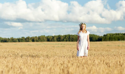 happy young woman in flower wreath on cereal field