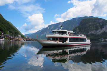 The ferry goes across lake Hallstatt, mountains as background, Austria.