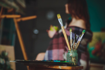 Closeup of painting brushes against the background of a woman ar