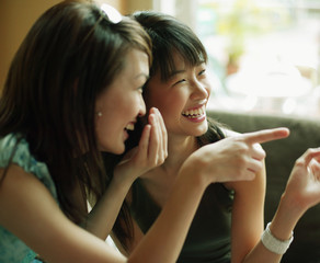 Young women whispering and pointing.
