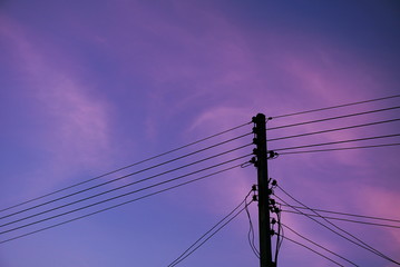 Fototapeta premium Silhouette electricity power lines over pink or purple sky in sunset