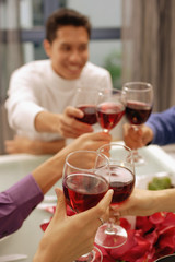 Friends toasting with wine glasses across dinner table