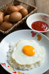 Fried egg on cooked rice and fresh eggs.
