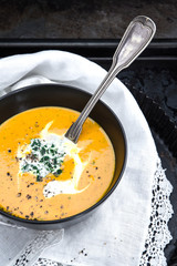 Kürbissuppe mit Sahne, Petersilie, Pfeffer und einem Esslöffel auf einem alten Backblech