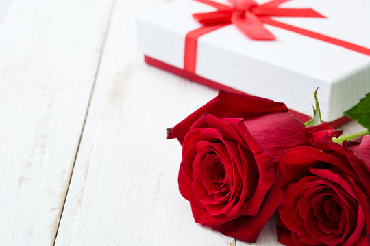 White gift box and roses on white wooden table.copyspace
