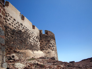 Medieval fortress wall on the hillside against the backdrop of deep blue sky. Teguise, Lanzarote, Canary Islands, Spain