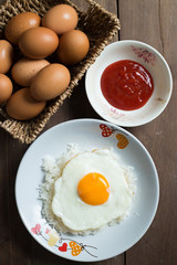 Fried egg on cooked rice and fresh eggs.