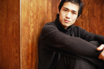 Fototapeta premium Young man sitting on floor, hugging knees
