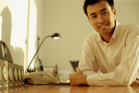 Executive sitting at desk, arms crossed