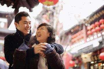 Young man embracing young woman, urban scene