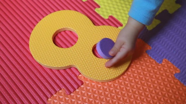 Bambino gioca con numero otto. Non riesce a incastrare un cerchio. Dopo ci riesce
