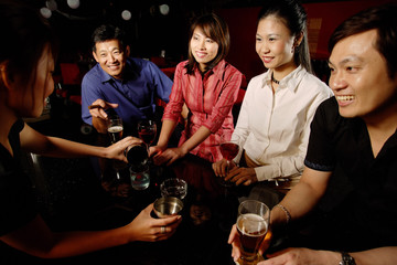 Couples drinking at bar, bartender serving them