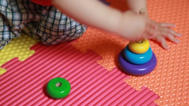 Bambino gioca con una piramide, infila gli anelli